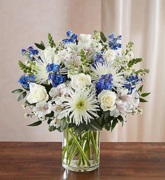 White and blue mixed bouquet in a clear glass vase