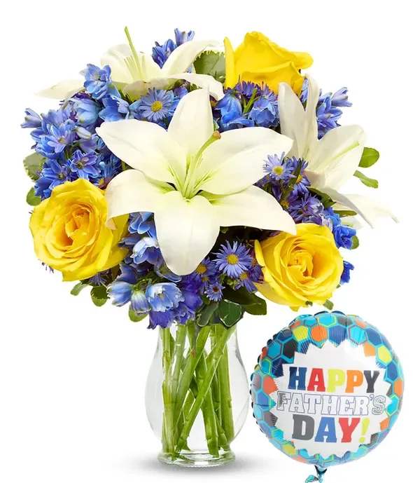 Bouquet of white lilies, yellow roses, and blue flowers in a glass vase with a Father's Day balloon