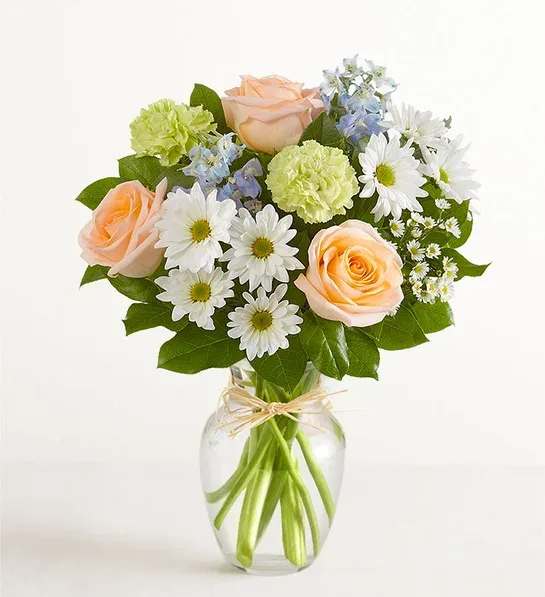 Peach roses and white daisies in a clear glass vase