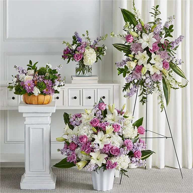 Three pastel floral arrangements with lilies and roses in vases and a basket