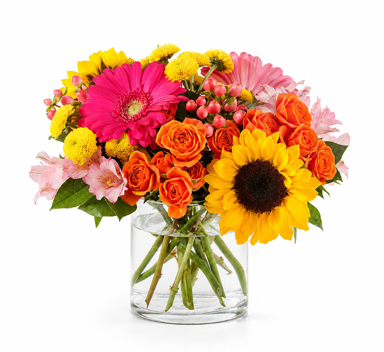 Bright mixed bouquet of roses, gerbera daisies, sunflowers, and mums in a glass vase