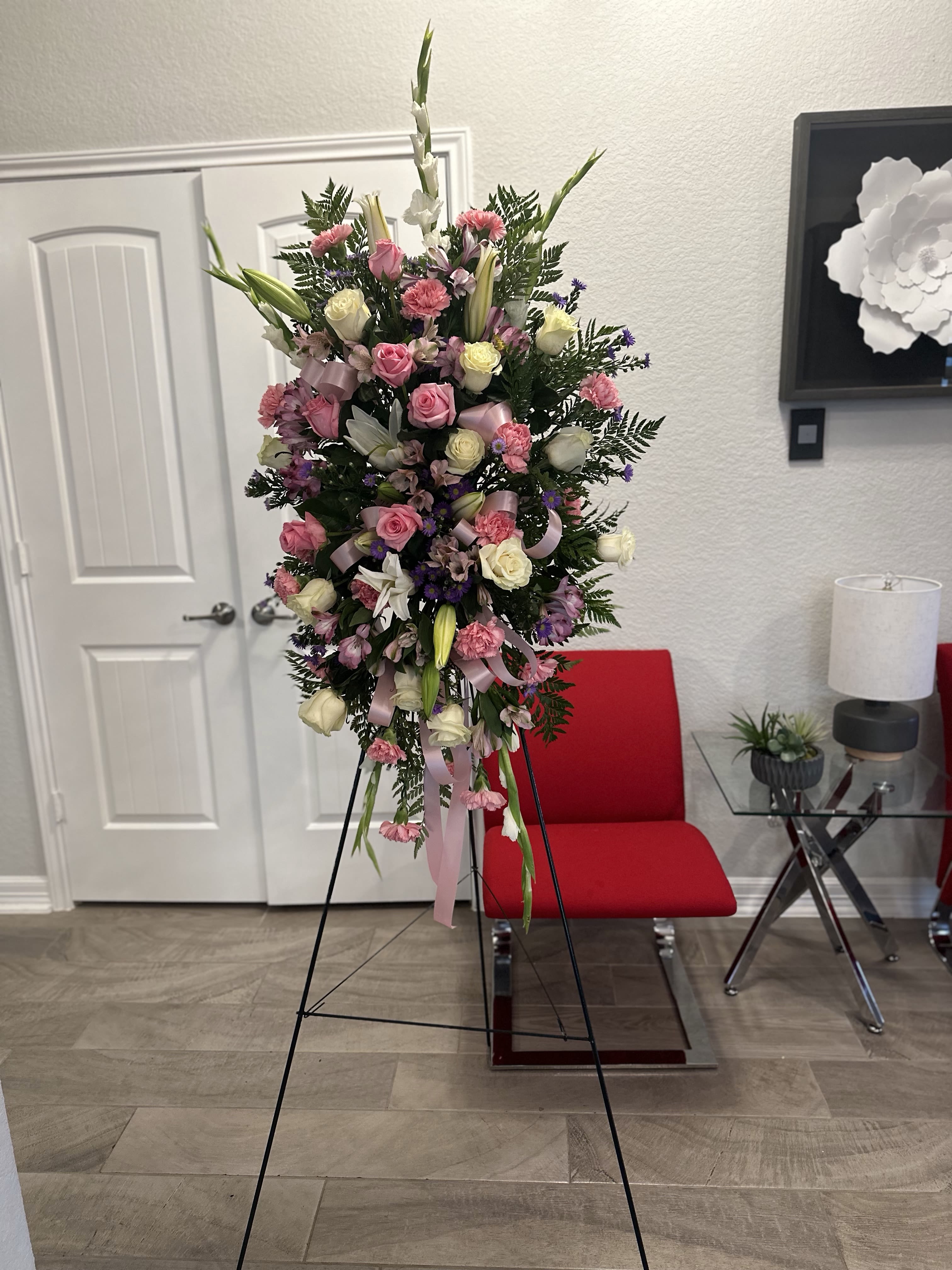 Tall pink and white standing spray of roses, lilies, and carnations on a metal easel