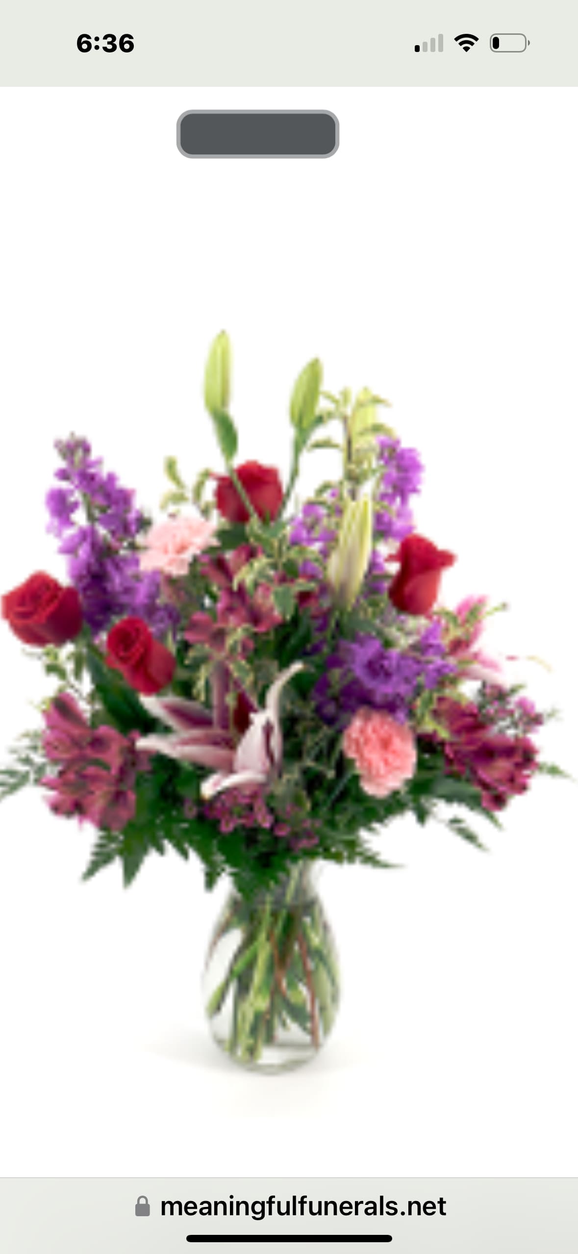 Tall mixed bouquet of red roses, pink lilies, and purple flowers in a clear glass vase