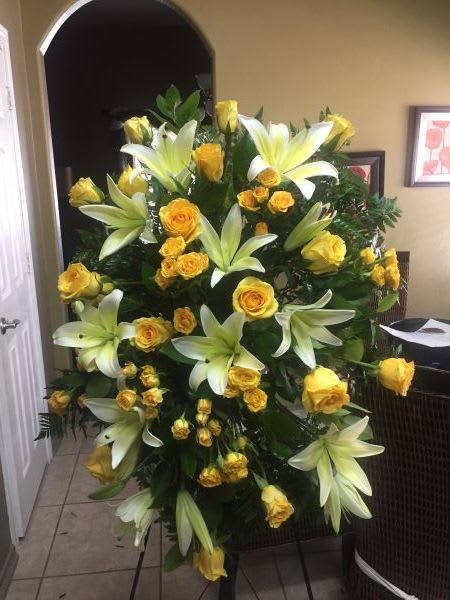 Tall standing spray of yellow roses and white lilies on an easel