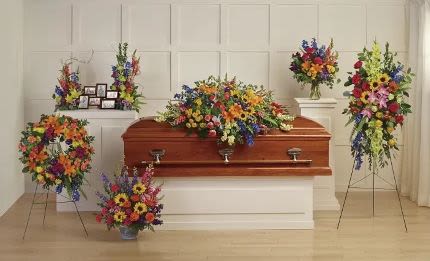 Sympathy set of colorful funeral sprays and wreaths surrounding a wooden casket