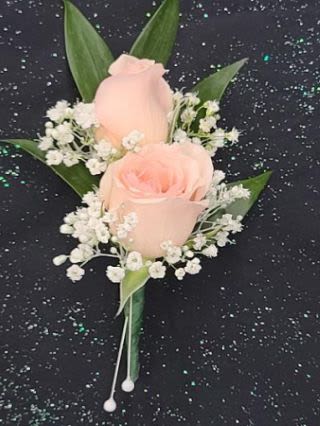 Peach rose boutonniere with white filler flowers on a black speckled background