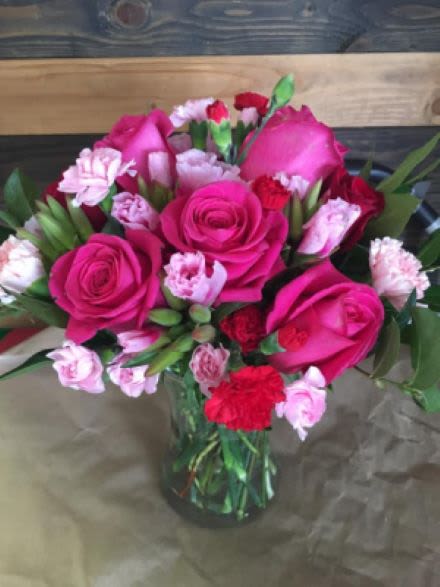Arrangement of hot pink roses and pink and red carnations in a clear glass vase