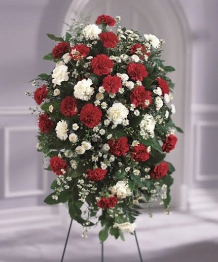 Standing spray of red and white carnations with white daisies on a metal easel
