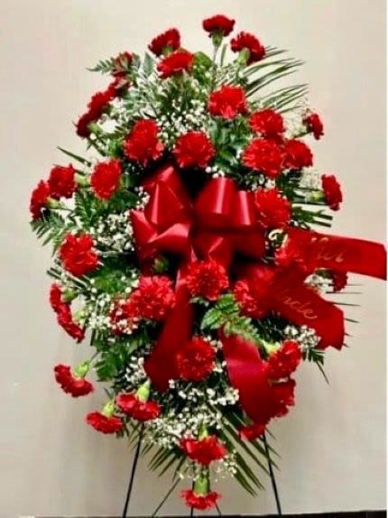 Tall standing spray of red carnations with a large red bow on an easel