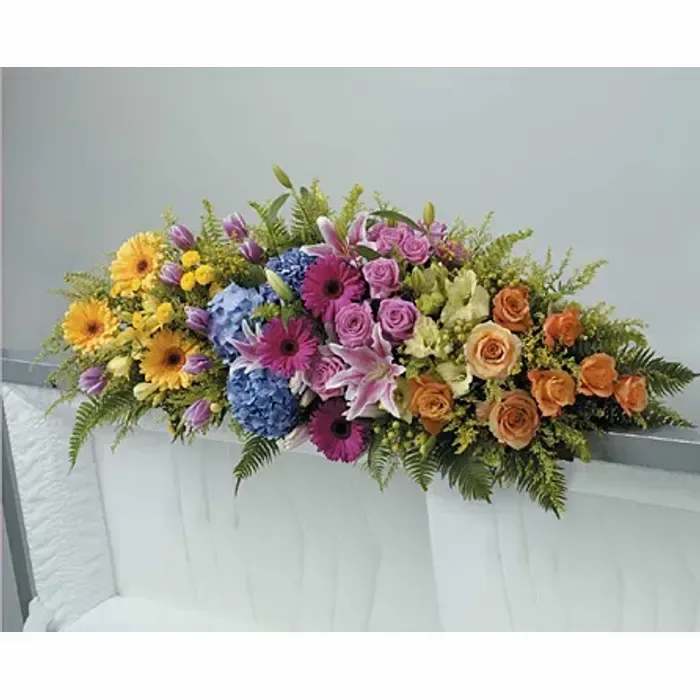 Colorful casket spray with pink lilies, roses, gerbera daisies, hydrangeas, and mixed blooms.