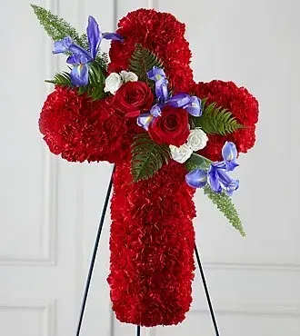 Standing red carnation cross with red roses, white blooms, and purple irises on a black easel