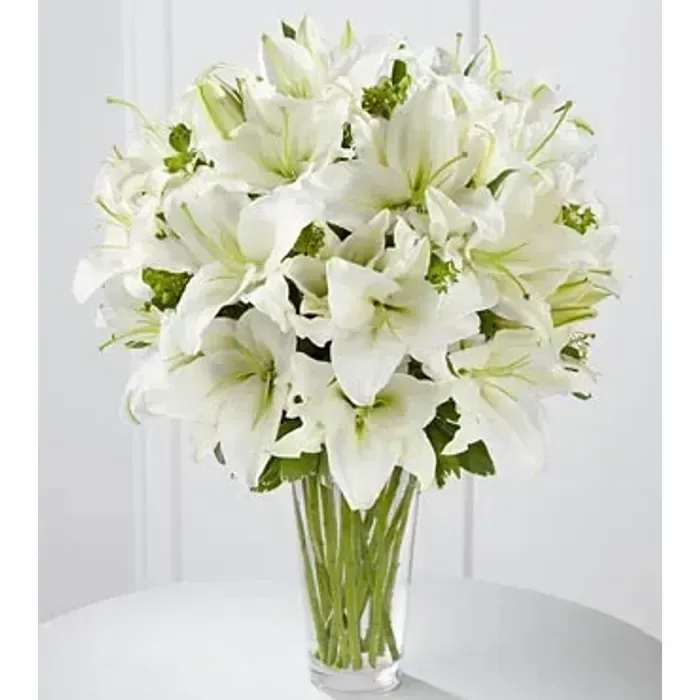 Tall arrangement of white lilies in a clear glass vase