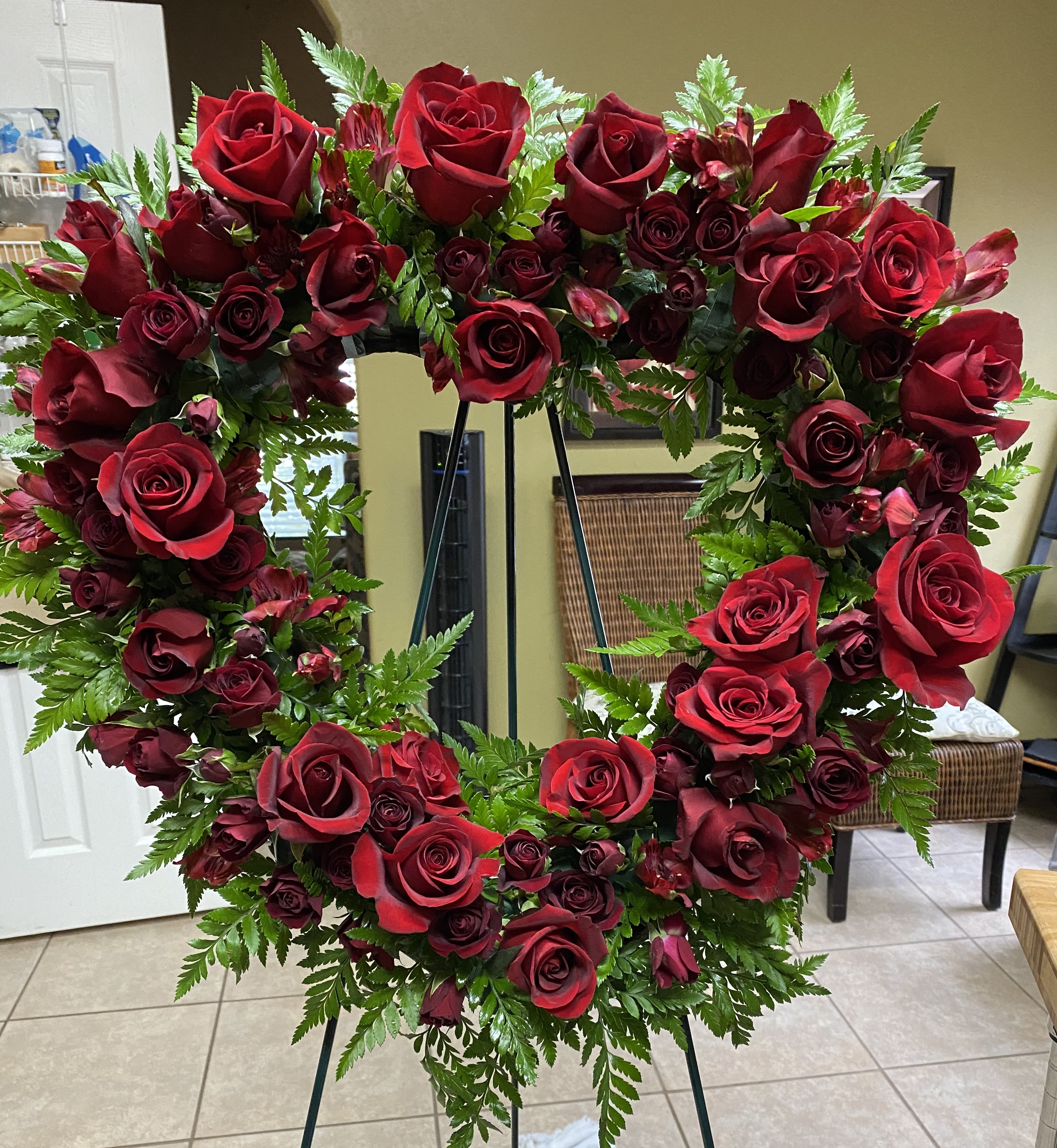 Heart-shaped wreath of red roses on a stand