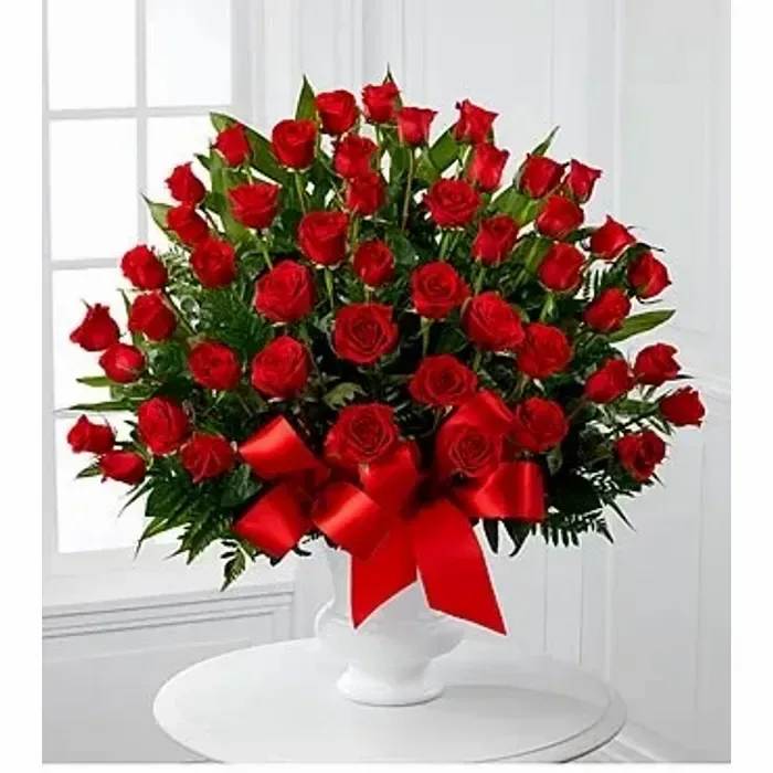 Large bouquet of red roses in a white vase with a red ribbon