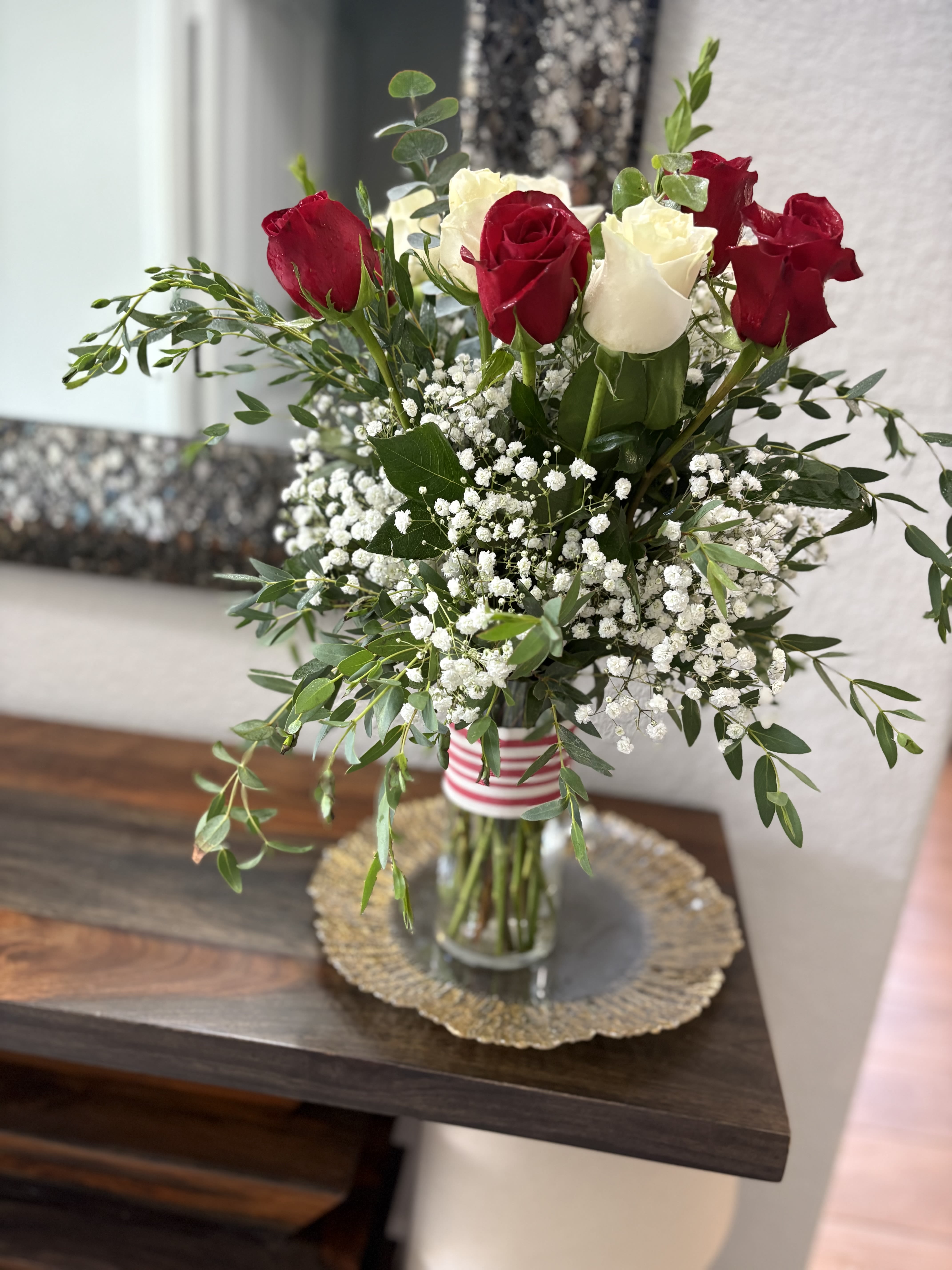 Red and white roses in a glass vase with baby's breath
