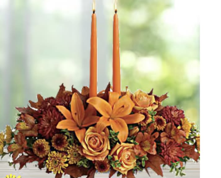 Orange floral centerpiece with two tall taper candles