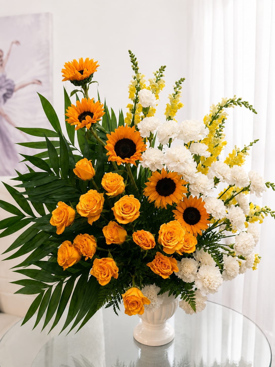 Golden Sunrise Tribute NEW - Honor a cherished life with the warm beauty of Golden Sunrise Tribute, a radiant standing floral arrangement that symbolizes hope, remembrance, and everlasting love. Vibrant golden sunflowers and rich yellow roses are beautifully complemented by elegant white carnations, cheerful yellow snapdragons, and lush tropical greenery. This impressive tribute offers a heartfelt expression of comfort and celebration of a life well live.
