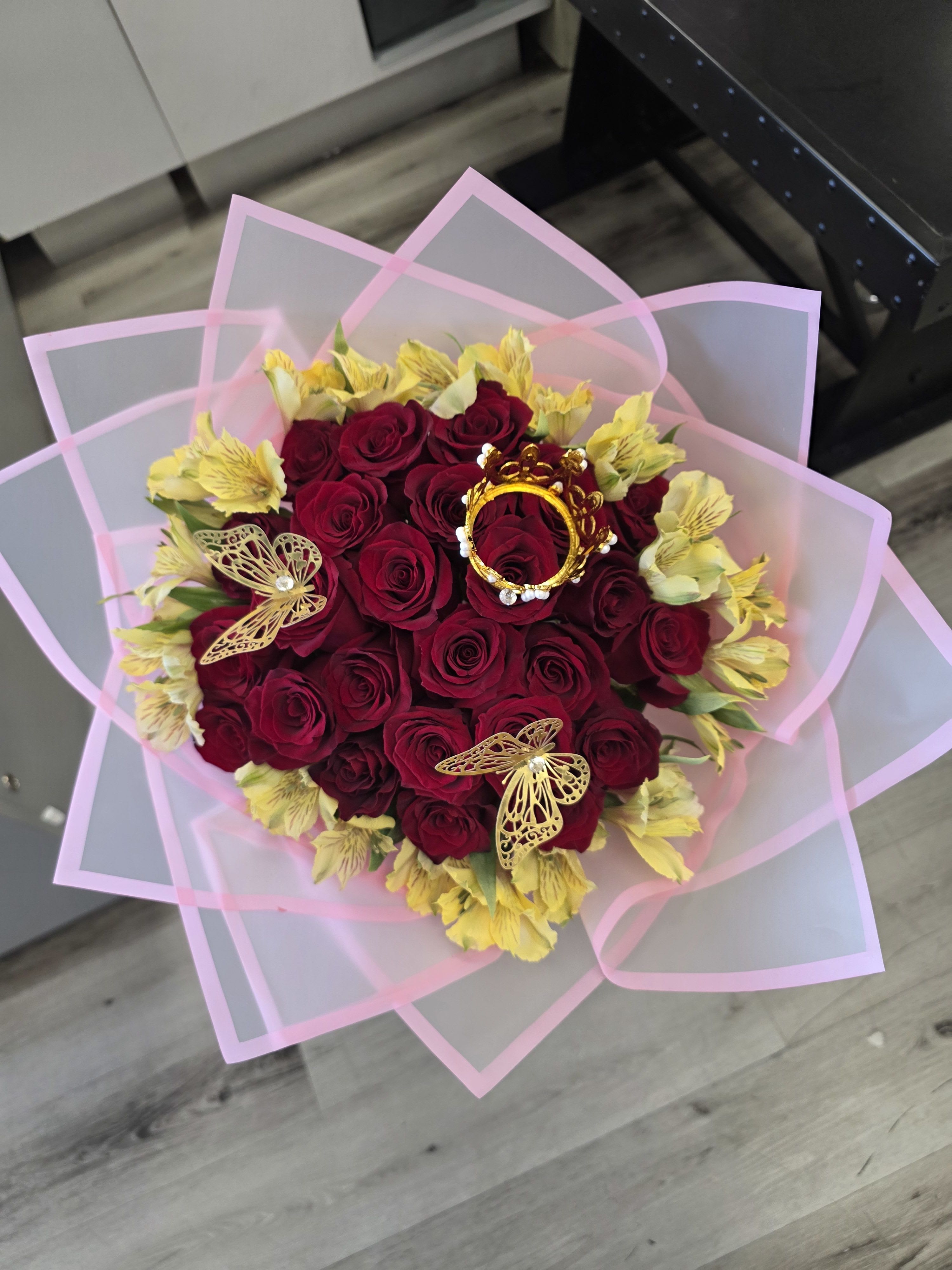 Bouquet of red roses with yellow flowers wrapped in pink paper