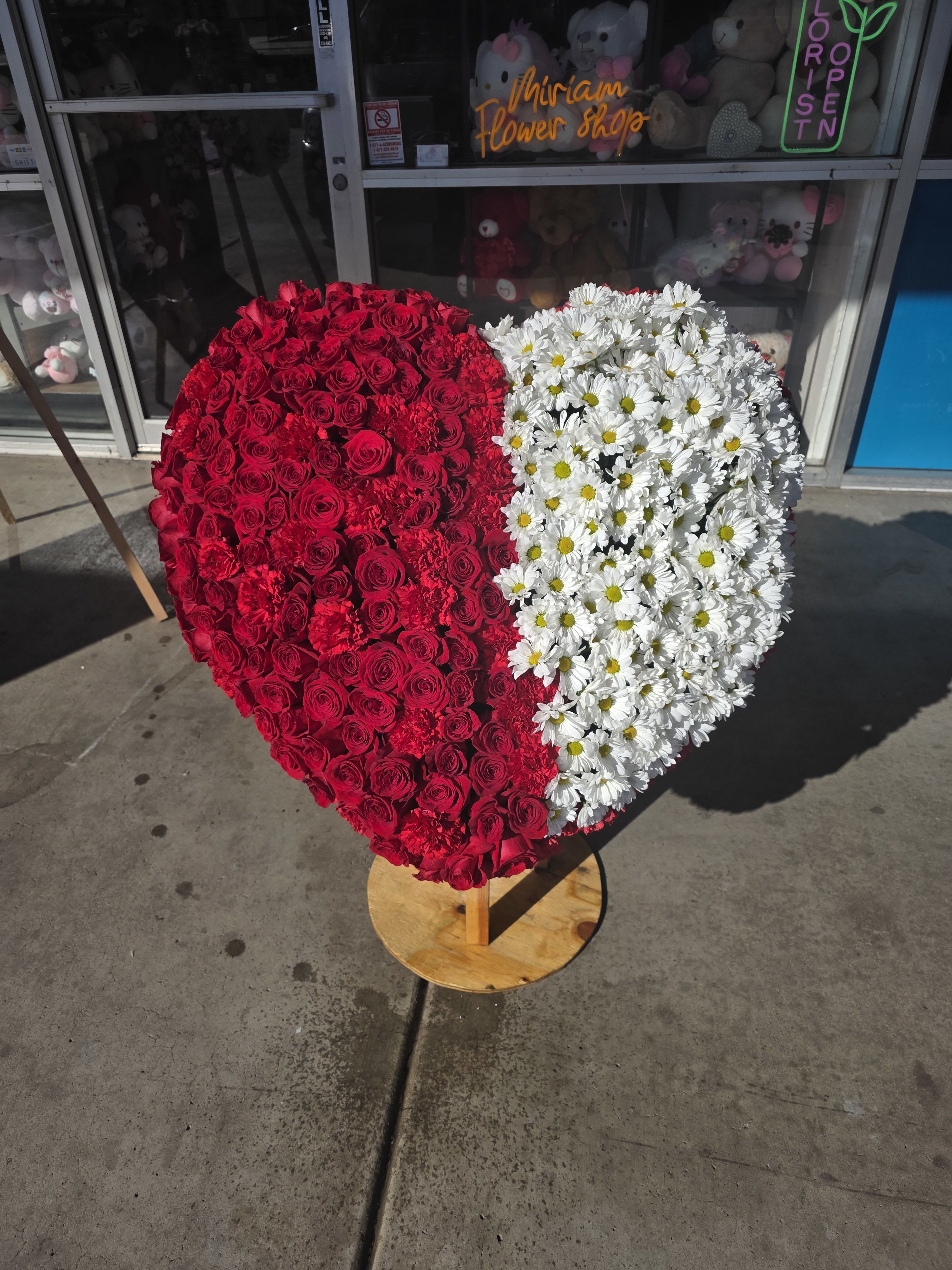 Heart-shaped floral arrangement with red roses and white daisies