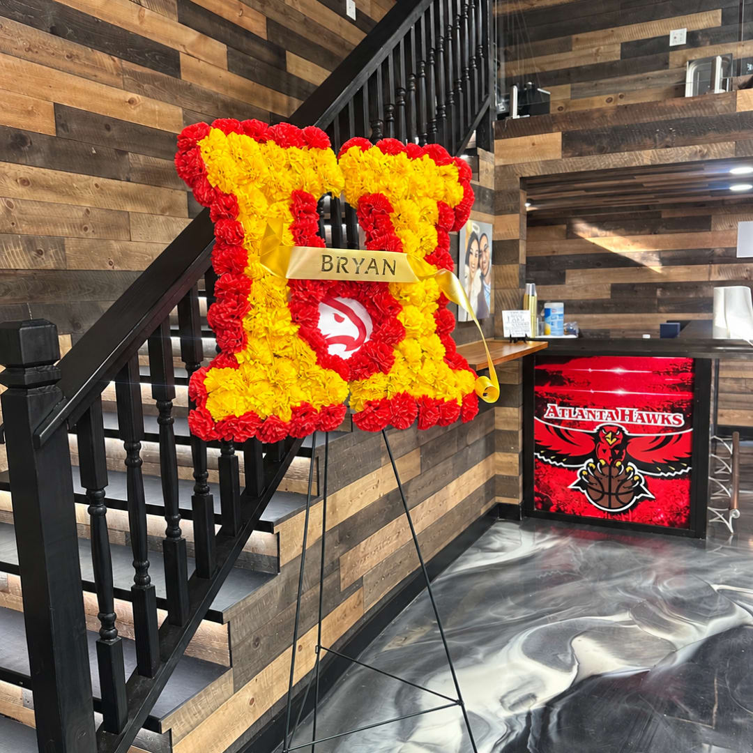 Heart-shaped red and yellow floral tribute on an easel with a gold ribbon