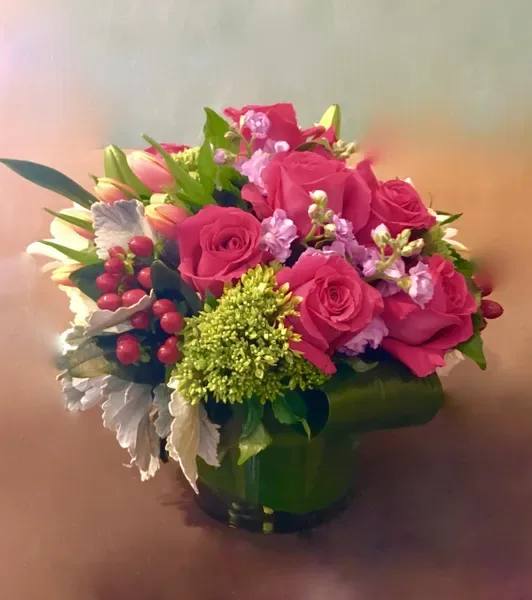 Pink roses and tulips arranged in a green vase