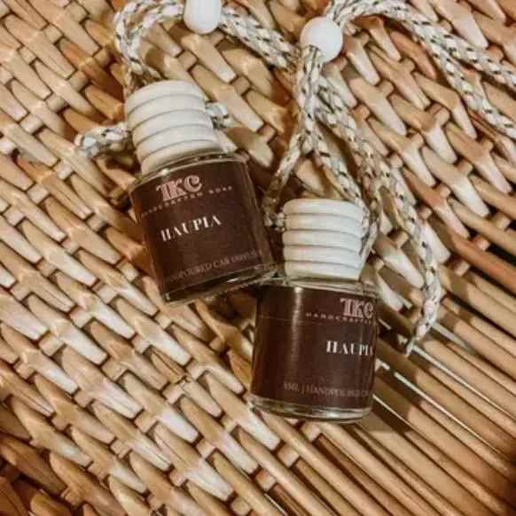 Two small brown glass perfume bottles with braided cords on a woven mat.