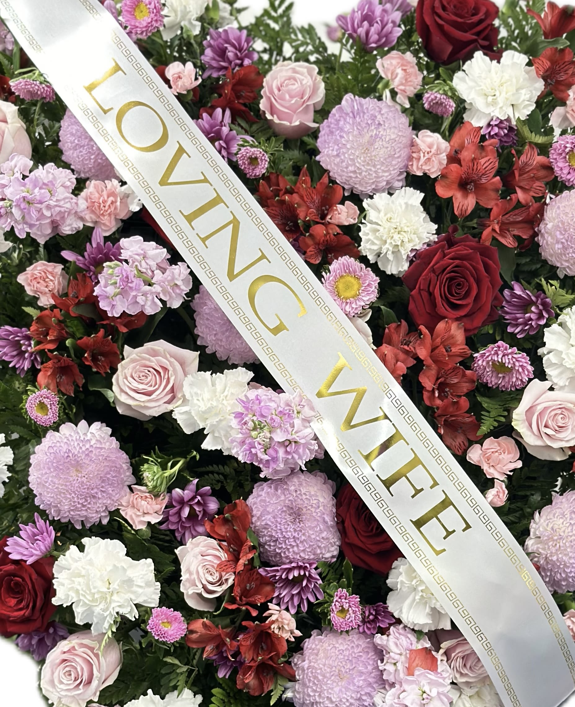 Floral arrangement with roses, chrysanthemums, and alstroemeria under a "LOVING WIFE" ribbon