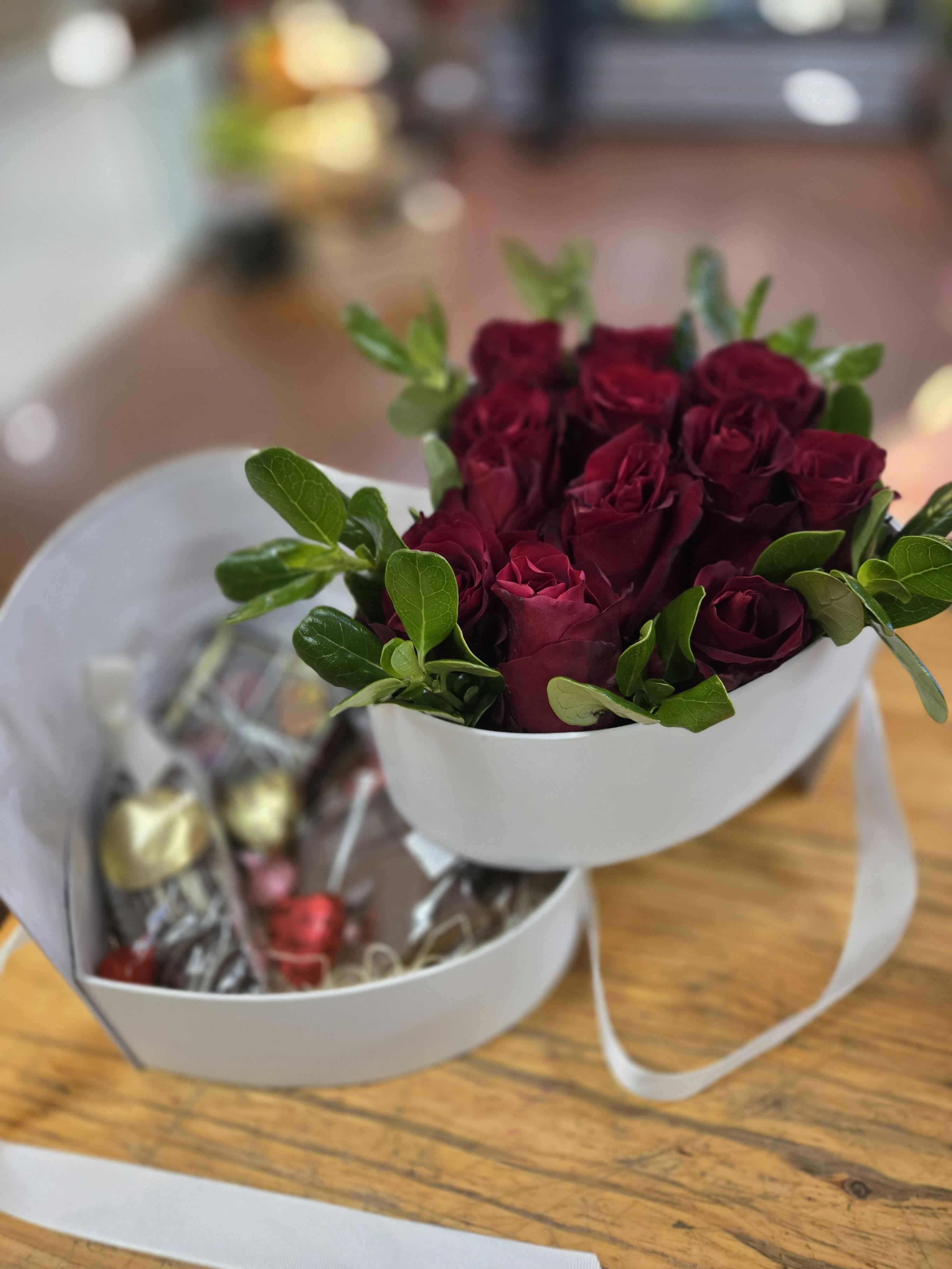 Bouquet of deep red roses with chocolates in white boxes