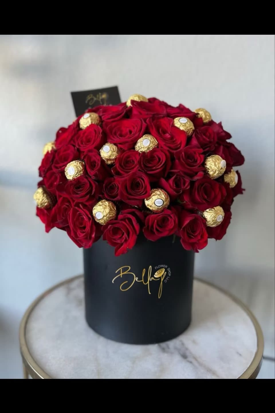 Red roses with gold-wrapped chocolates in a black hat box
