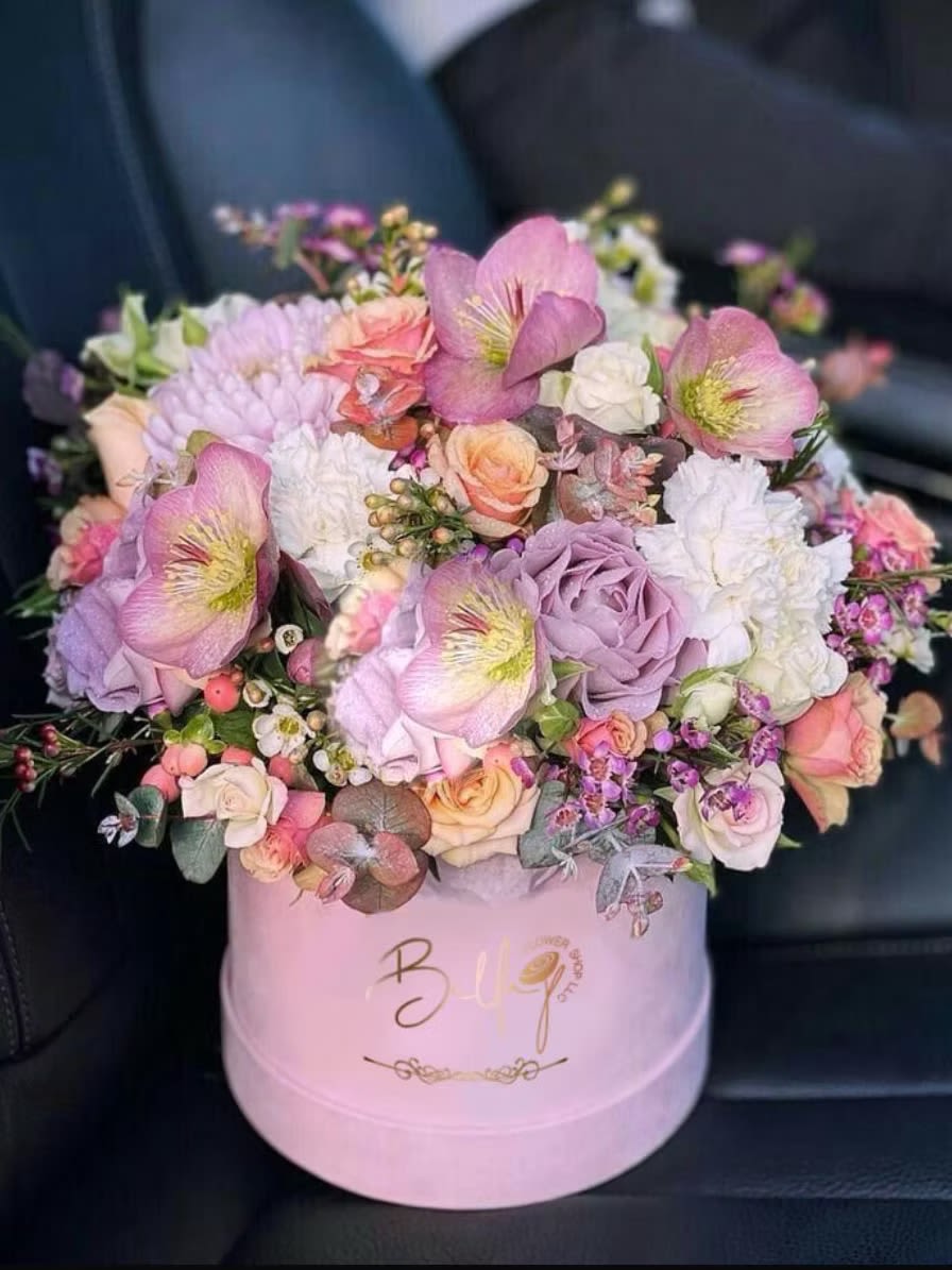 Pink and lavender flower arrangement in a round hat box