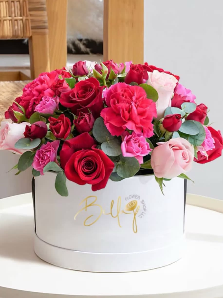 Bouquet of red and pink roses with carnations in a white box