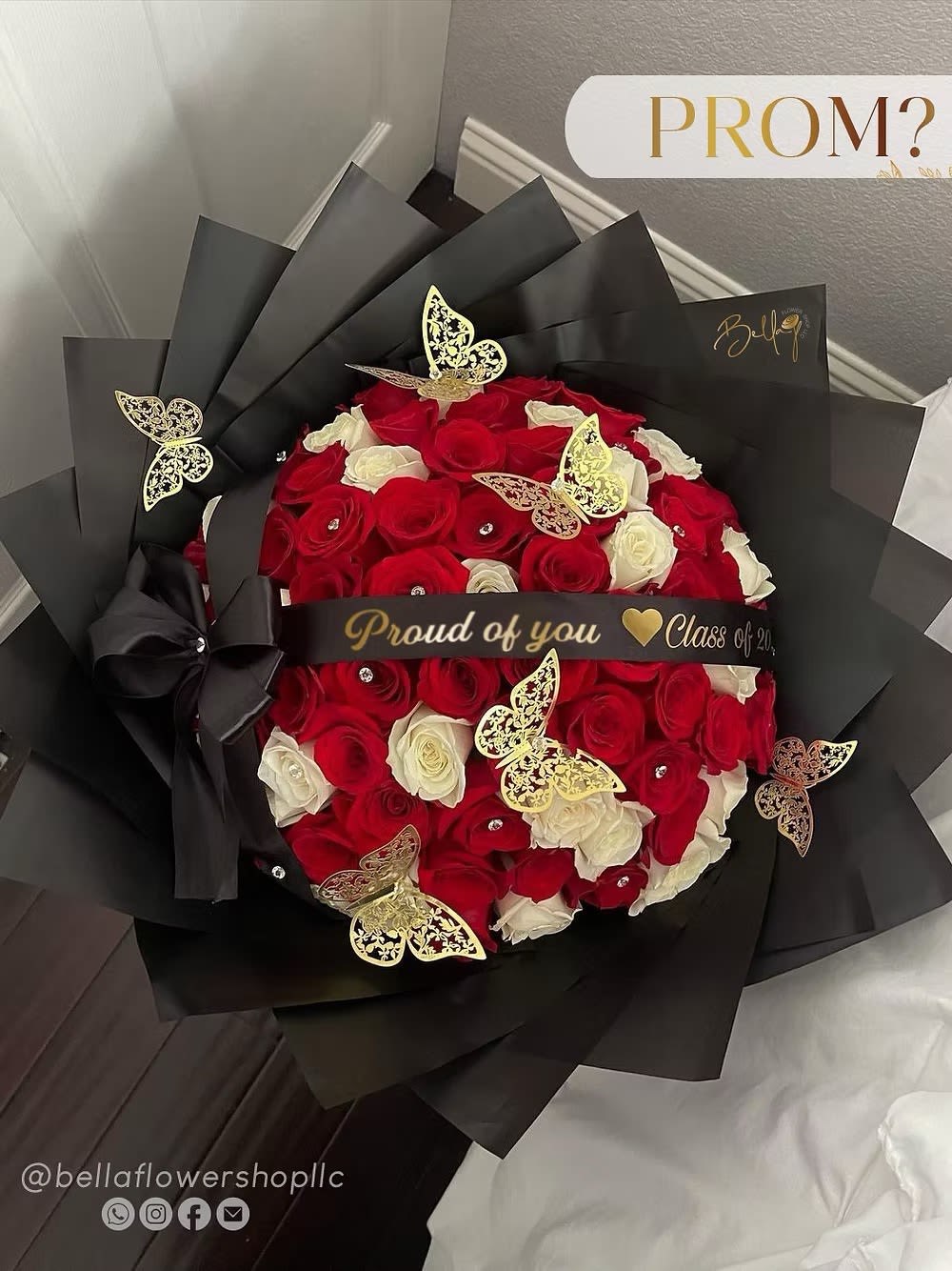 Bouquet of red and white roses wrapped in black paper with gold butterfly accents