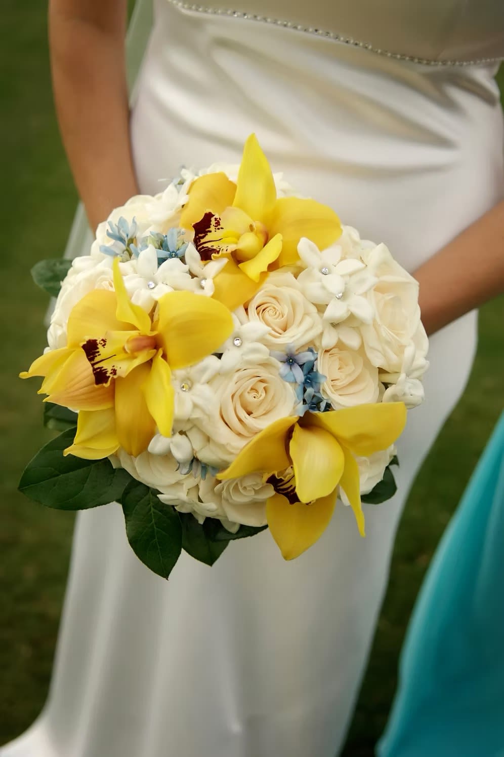 Bridal bouquet with yellow orchids, white roses, and small blue flowers