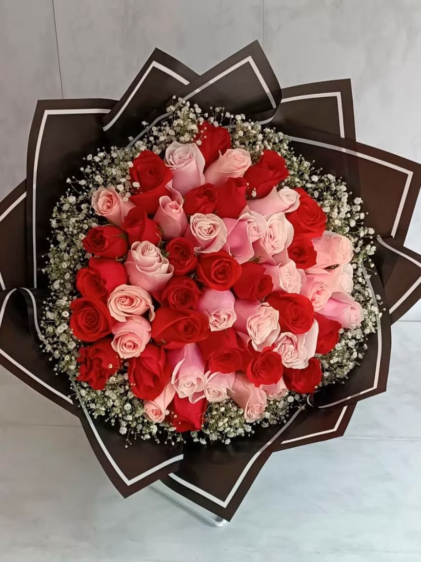 Bouquet of red and pink roses wrapped in dark paper