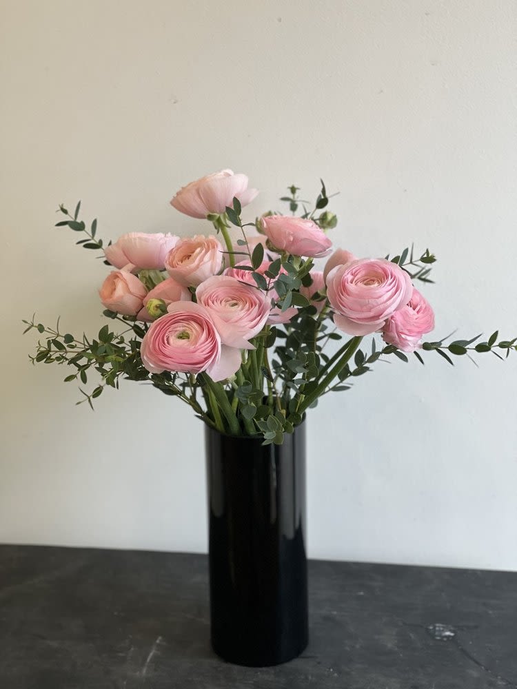 Pink ranunculus bouquet in a tall black vase