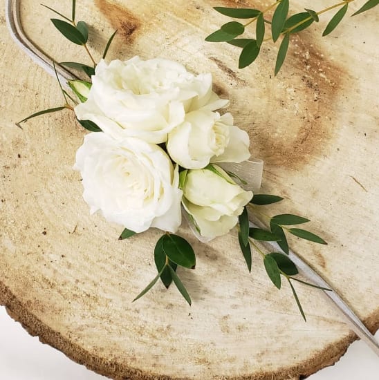 White rose bouquet with greenery on a rustic wood slice