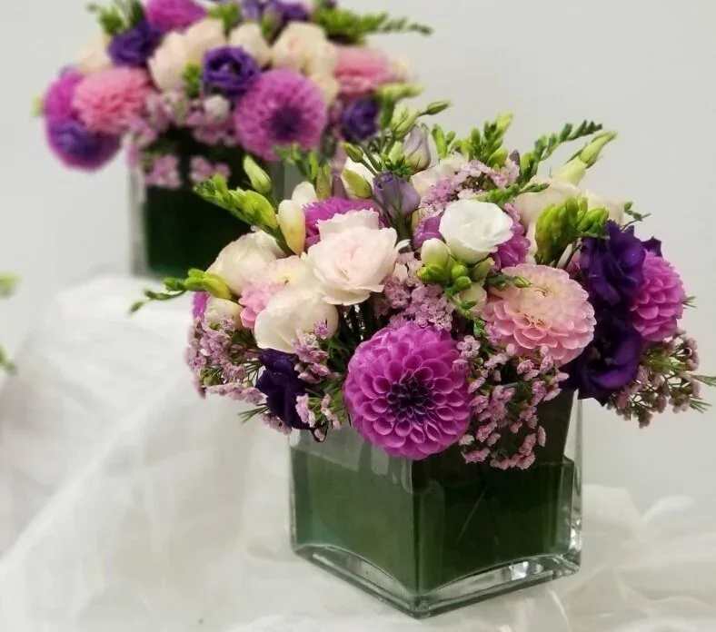 Pink, purple, and white flowers arranged in a square glass vase