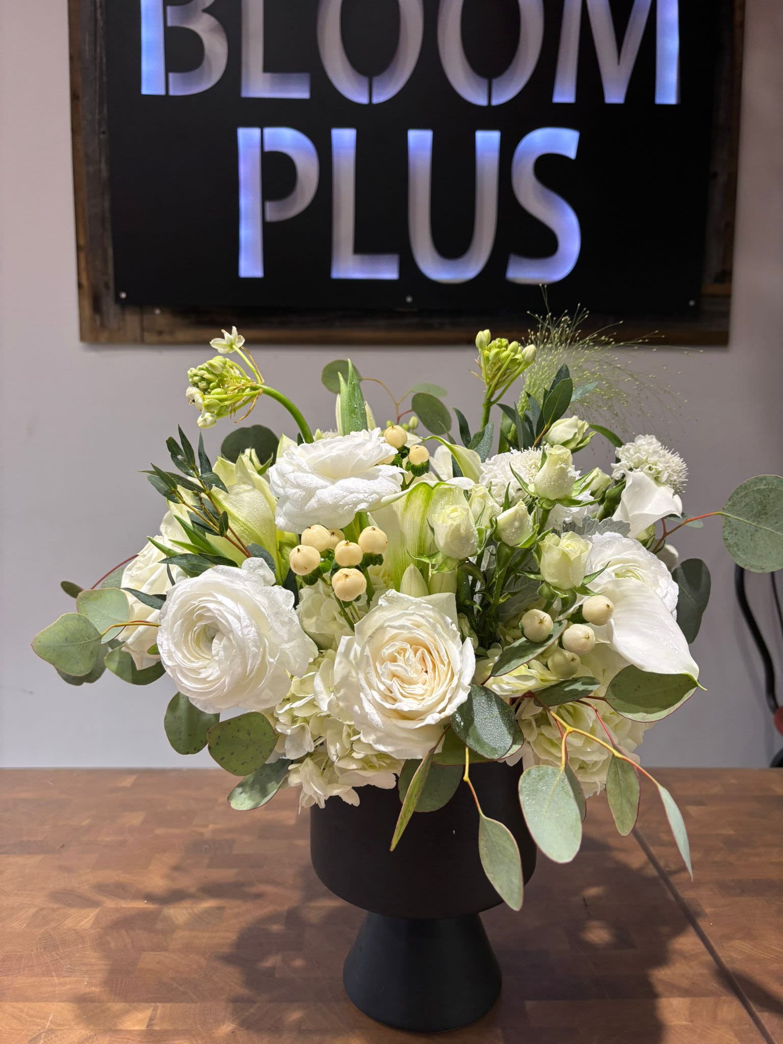 White floral arrangement in a black pedestal vase