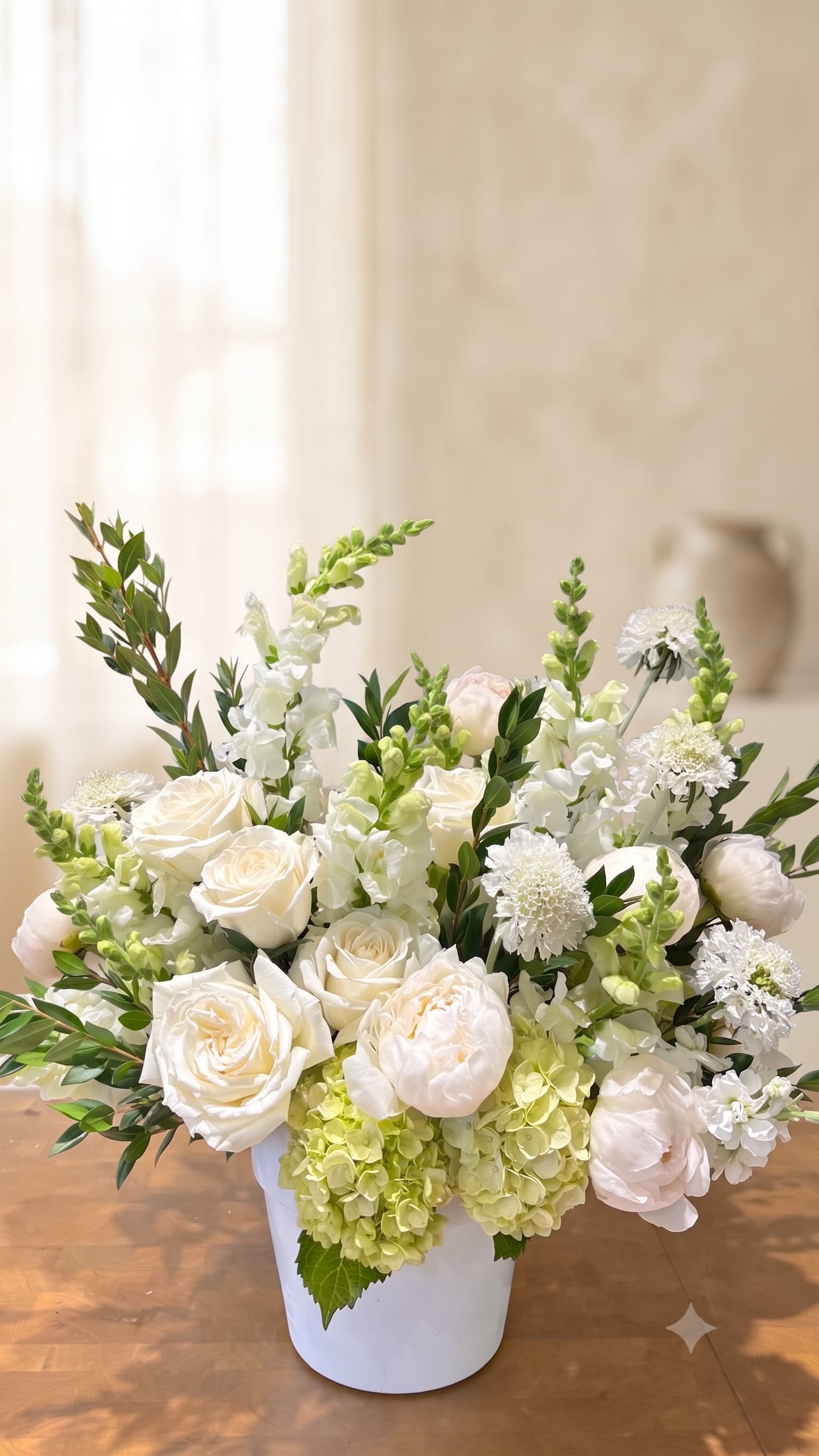 BP96 - Simple Peace - An elegant sympathy arrangement in a serene white and green palette.   For a Service: Arranged in a traditional funeral basket. (refer to Deluxe price's photo)  For Home Delivery: Arranged in a clear cylinder / white vase. (refer to Standard price's photo)  Please specify in the order comments whether this is intended for a funeral service or a home delivery so we can prepare the appropriate container.  Please Note: Due to seasonal availability, specific flower varieties may occasionally be substituted.