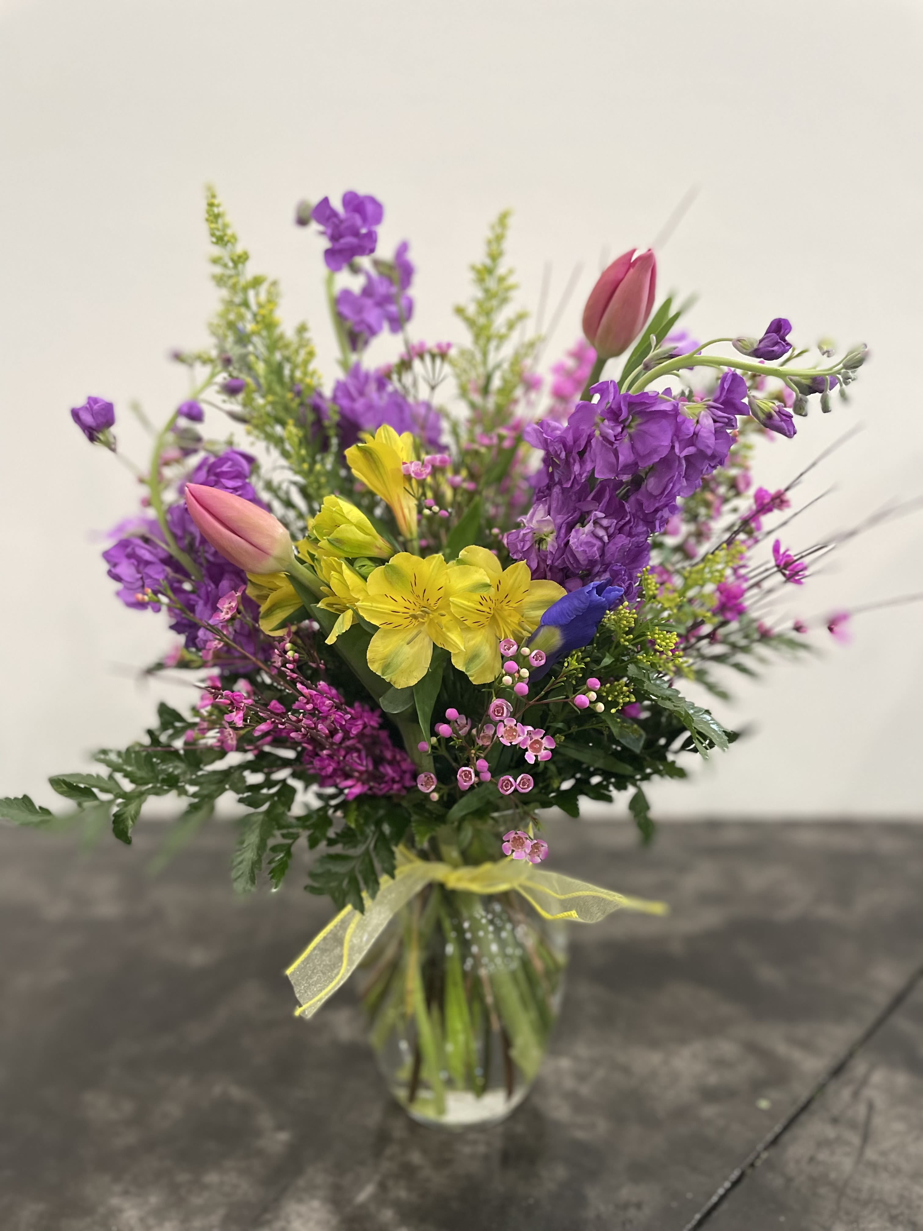 Colorful bouquet of purple, yellow, and pink flowers in a glass vase
