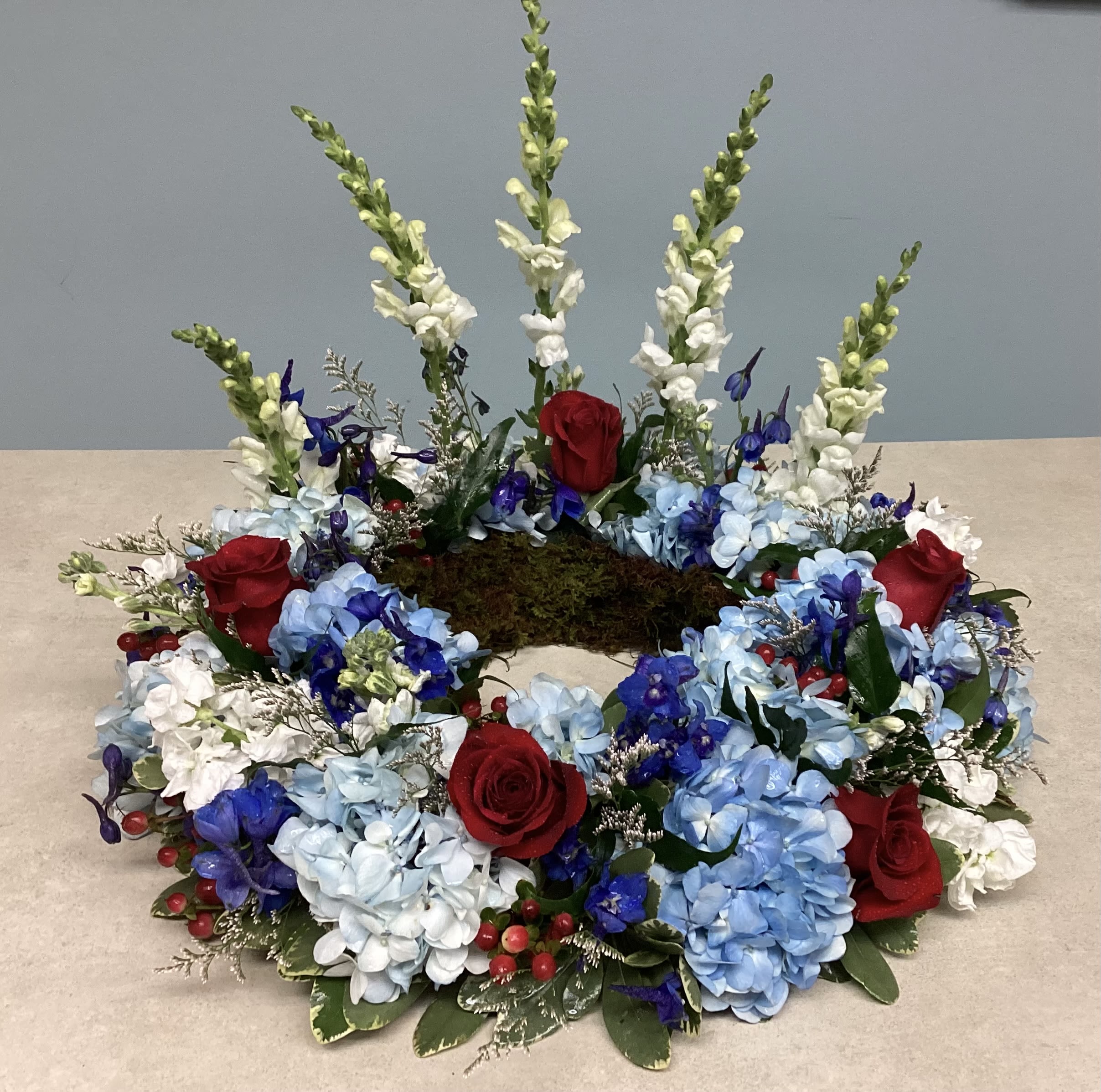 Beloved Patriot Sympathy Urn Wreath  - Honor your beloved patriot with this lush presentation in red, white and blue to include hydrangea, snapdragons, delphinium, roses and hypericum.