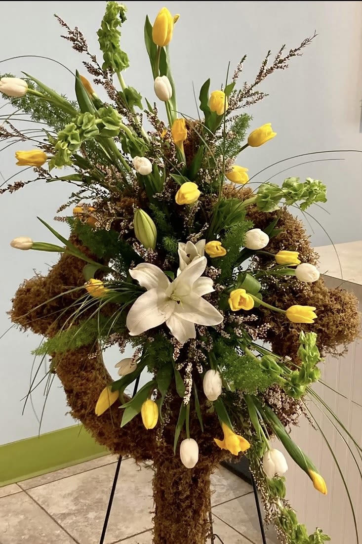 Celtic Cross - Yellow and white tulips with a central white lily, airy green accents and mossed base on a metal stand.