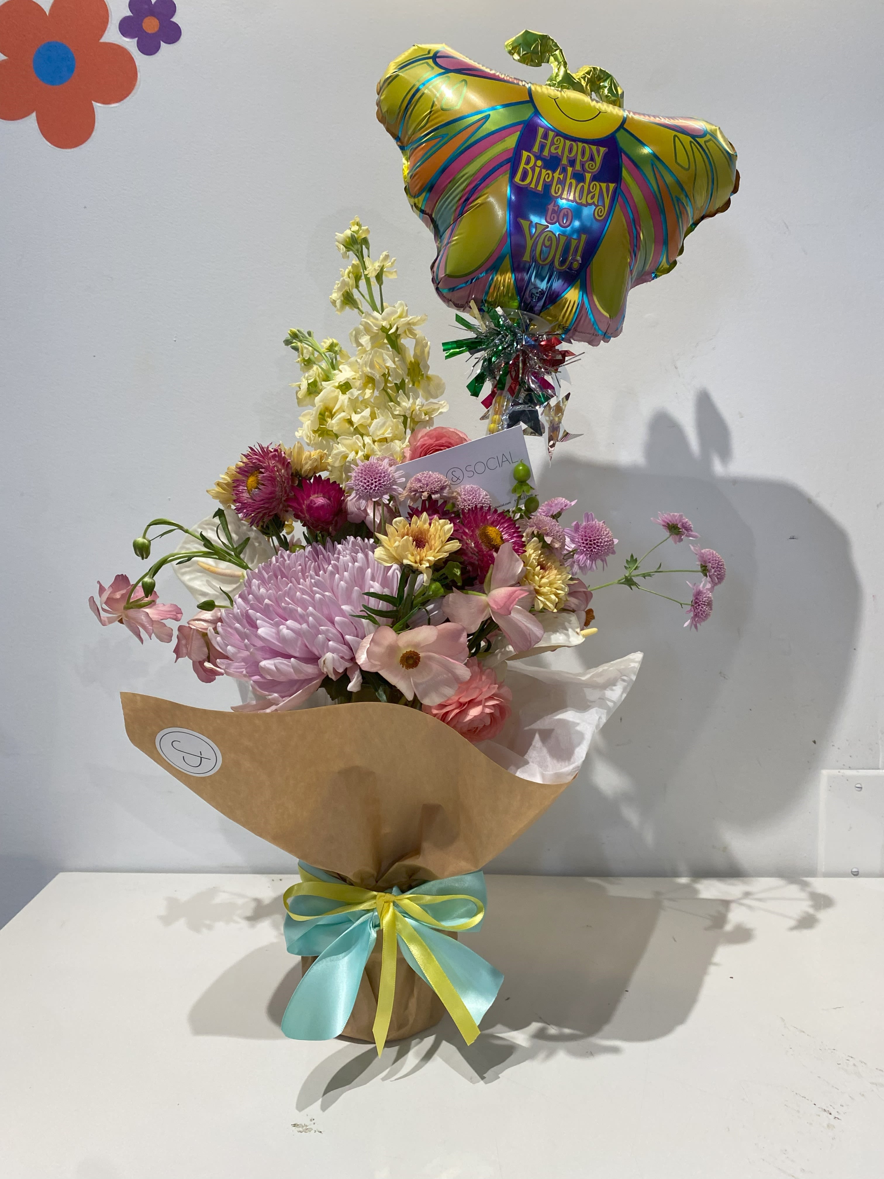 Whimsy Birthday - A whimsical assortment of festive blooms with a birthday balloon, unique fillers, and dried goods. A more unique, artsy arrangement than your typical delivery. Drop a note for a bit of direction or let our designers flex their talents. A mix of designer’s choice seasonal color blooms of Lisianthus, Mum, Rose, Alstroemeria, Hydrangea nestled in assorted greens and Eucalyptus. 