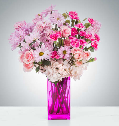 Pink mixed flowers arranged in a tall magenta vase