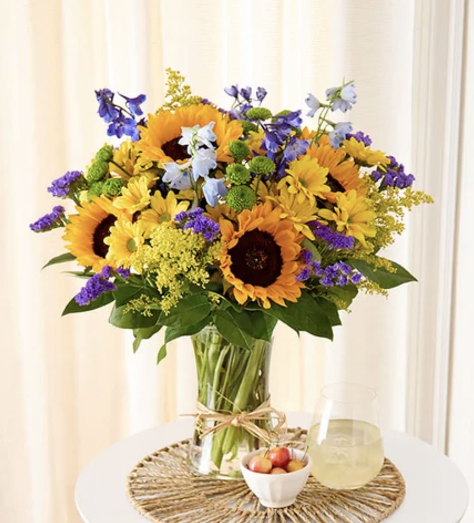 Sunflower bouquet in a glass vase with purple and blue accent flowers