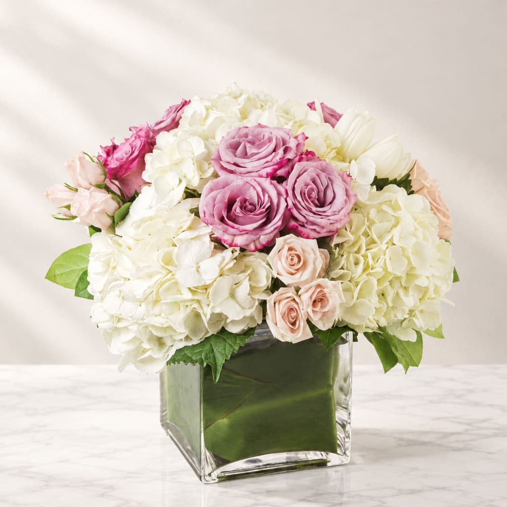 Pink roses and white hydrangeas arranged in a clear square vase