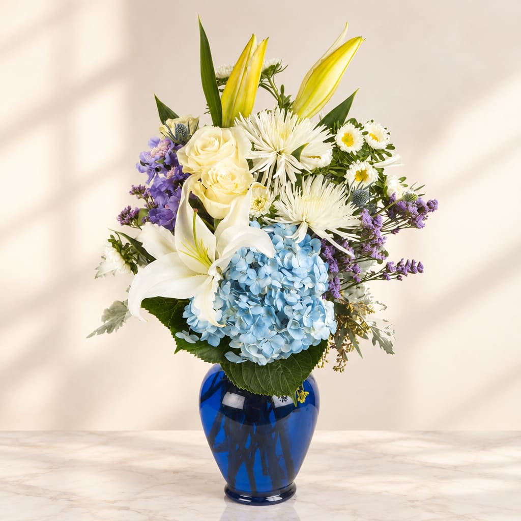 Bouquet of white lilies, roses, and blue hydrangea in a blue vase