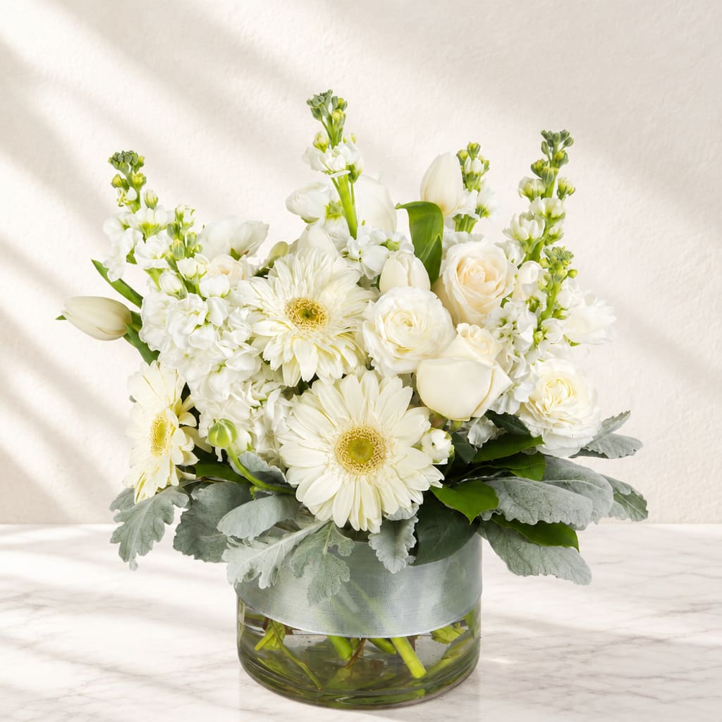 White flowers arranged in a glass vase with silver ribbon