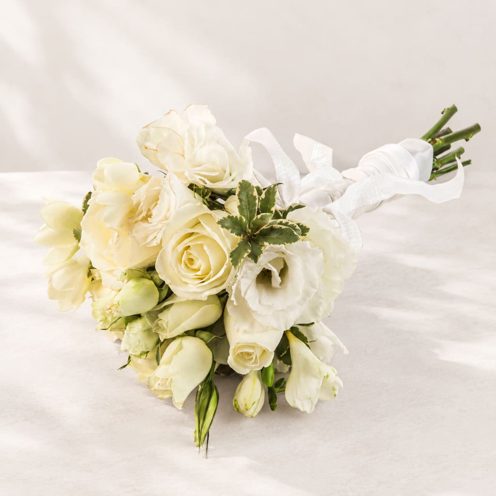 White bridal bouquet with roses and lisianthus tied with a white ribbon