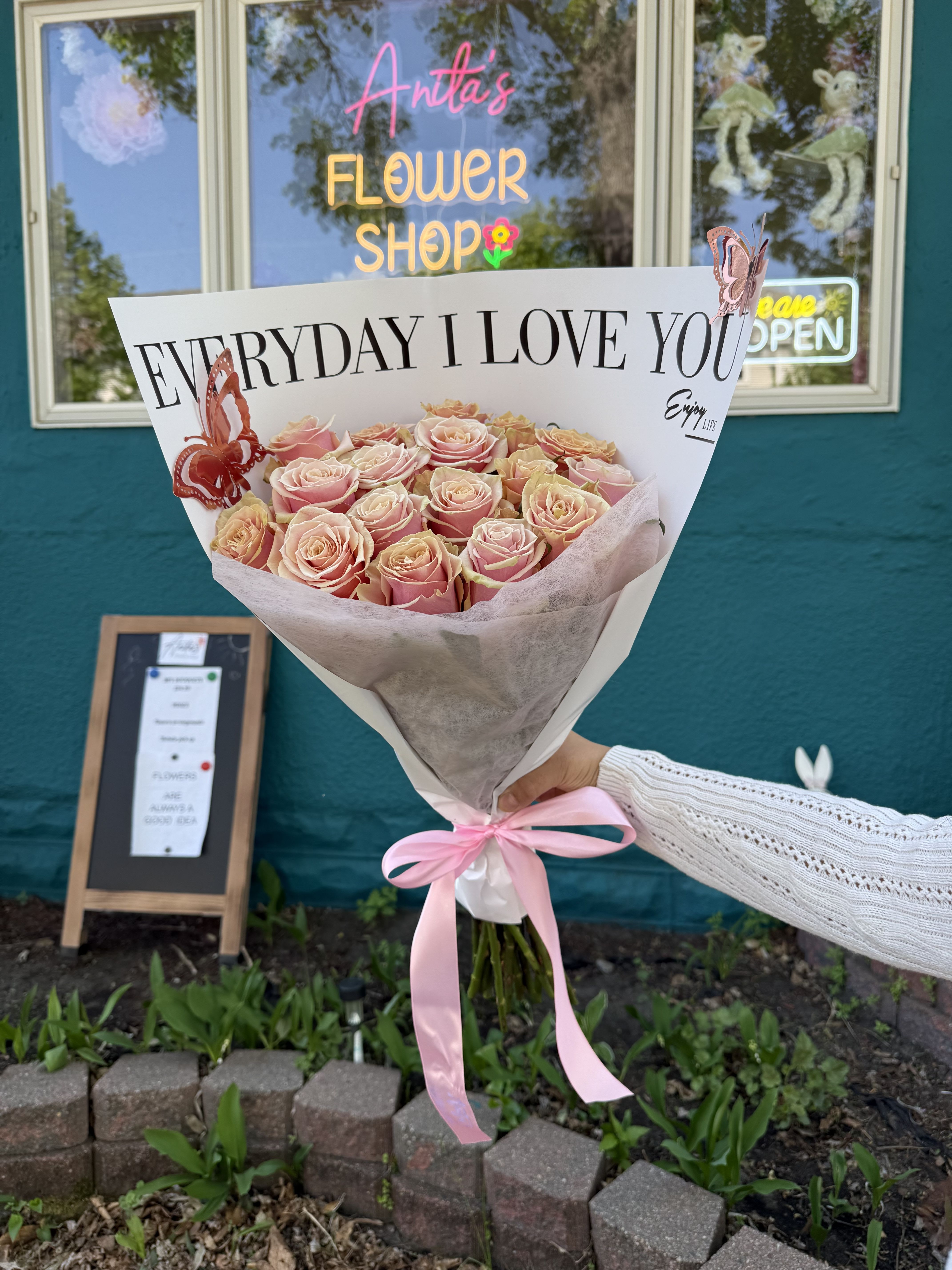 Bouquet of pink and peach roses wrapped in white paper with a pink ribbon